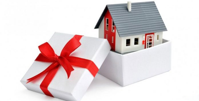 hình ảnh hộp quà buộc nơ đỏ được mở ra, bên trong chứa mô hình ngôi nhà minh họa cho việc tặng cho bất động sản