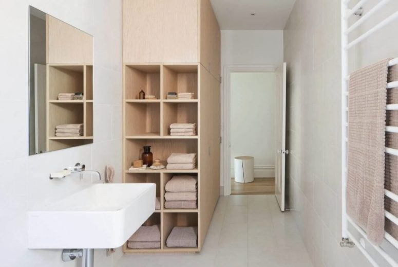Hệ tủ kệ bằng gỗ cao kịch trần được thiết kế gọn gàng ở góc phòng tắm, mang đến không gian lưu trữ rộng lớn cho gia chủ.