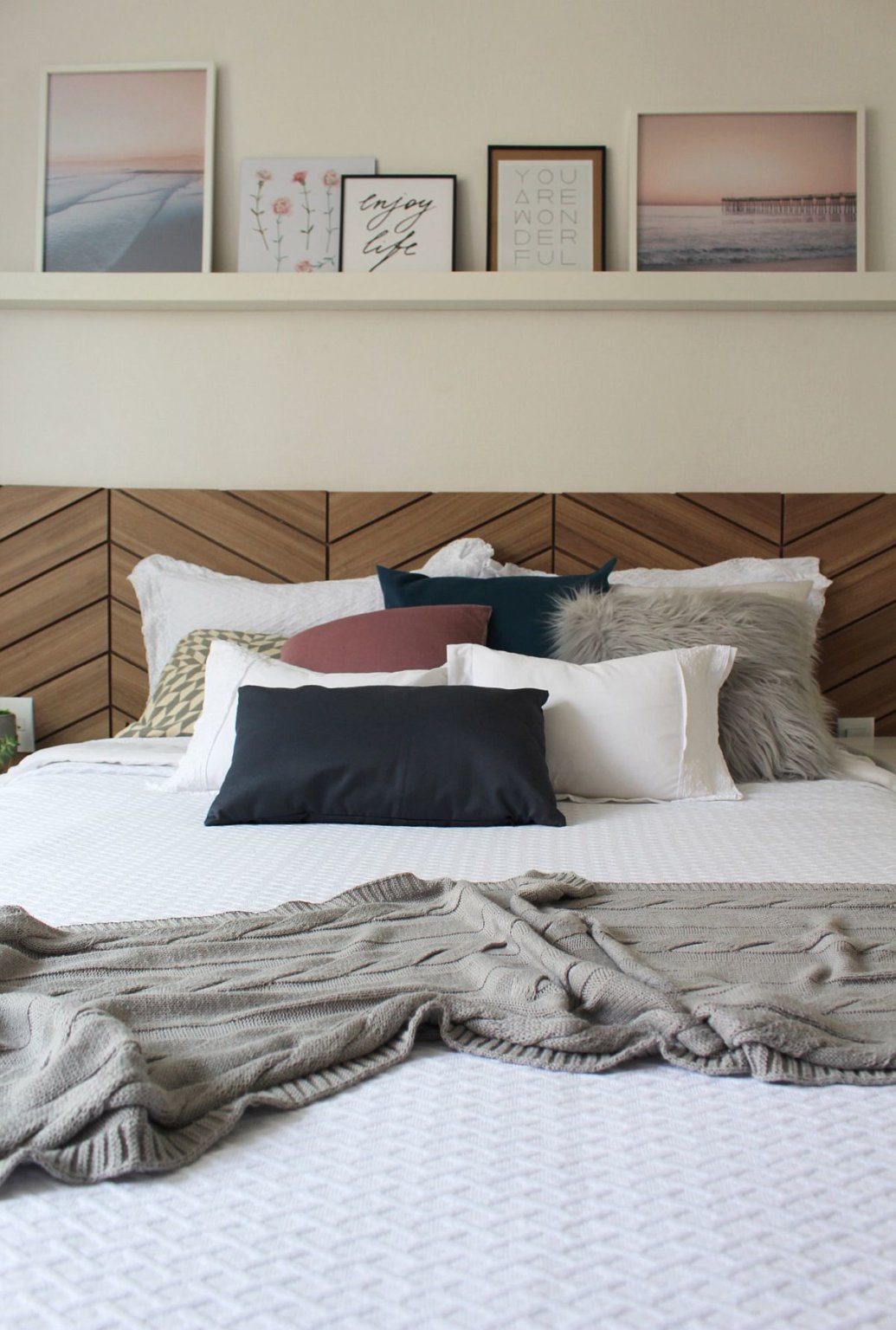 Tường đầu giường được decor tinh tế với kệ mở đặt bộ tranh cảnh biển hoàng hôn.