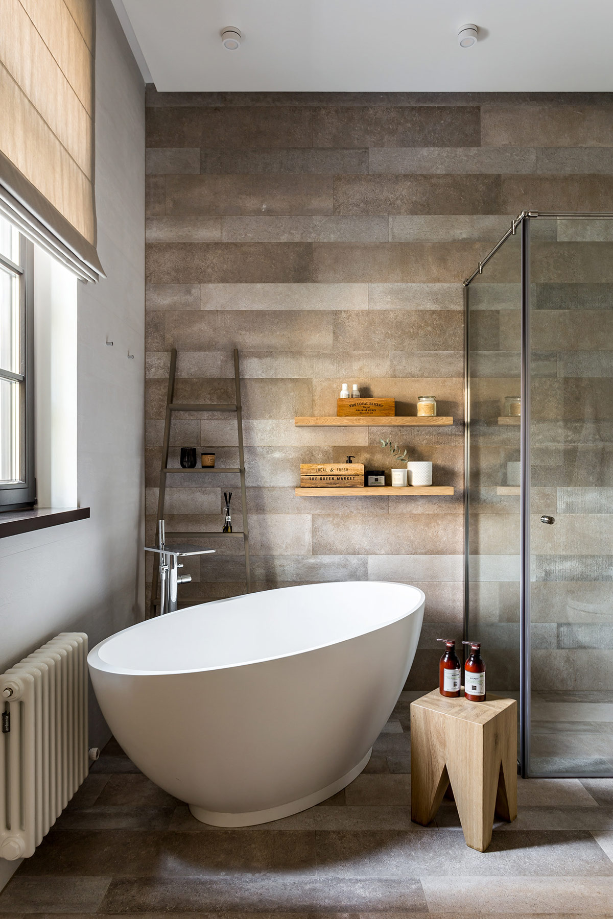Một bồn tắm độc lập nằm vừa khít trong góc phòng, nơi nhận được ánh nắng mặt trời trực tiếp trong ngôi nhà phong cách Rustic.