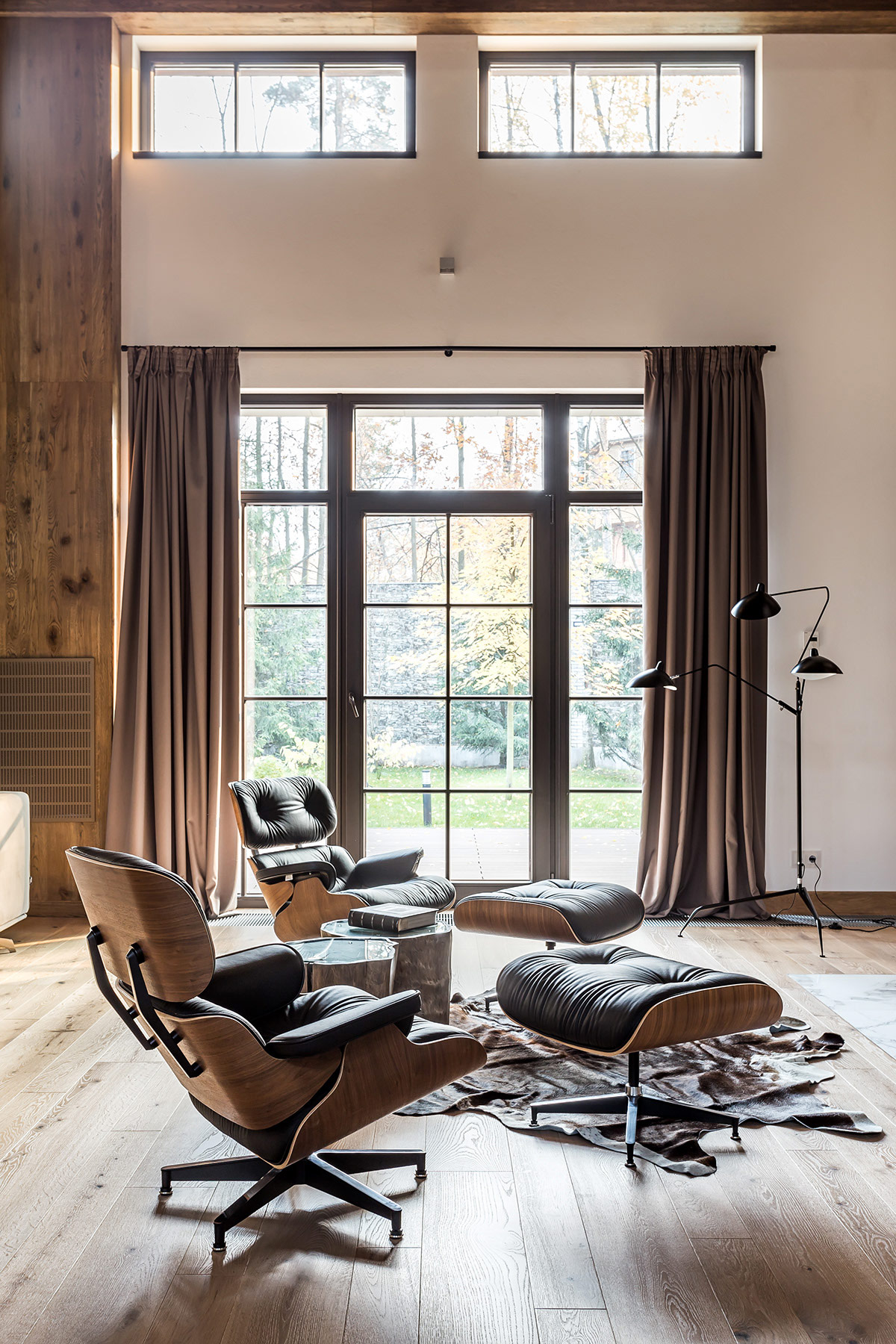 Hai chiếc ghế salon kiểu Eames và ghế đôn phù hợp để các thành viên gia đình quây quần bên lò sưởi ấm áp.