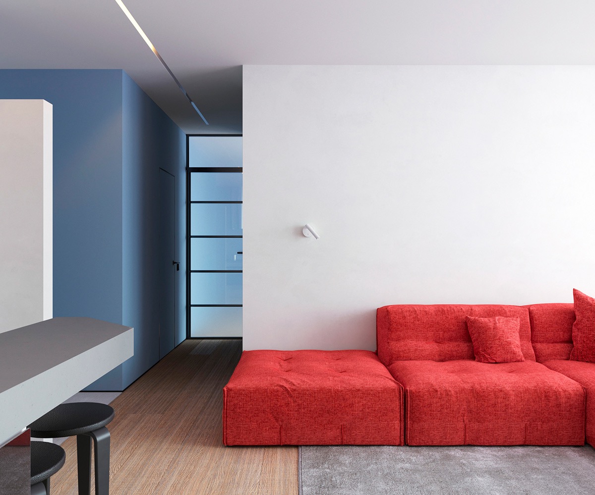 Trong phòng khách căn hộ 64m2, ghế sofa màu đỏ chiếm ưu thế trong khu vực chung, mọi thứ khác được loại bỏ ngoại trừ chiếc đèn treo tường hiện đại màu trắng.