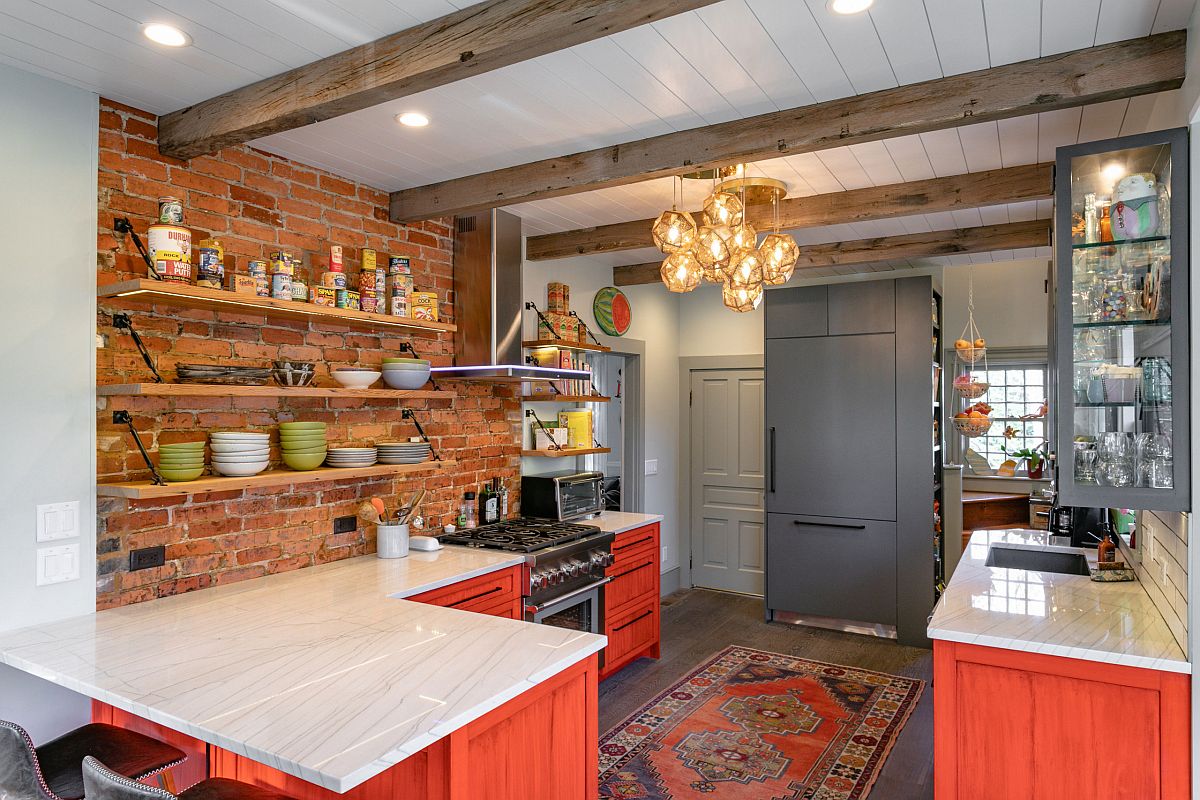phòng bếp với tường gạch lộ, dầm gỗ, tủ bếp sơn màu đỏ cam