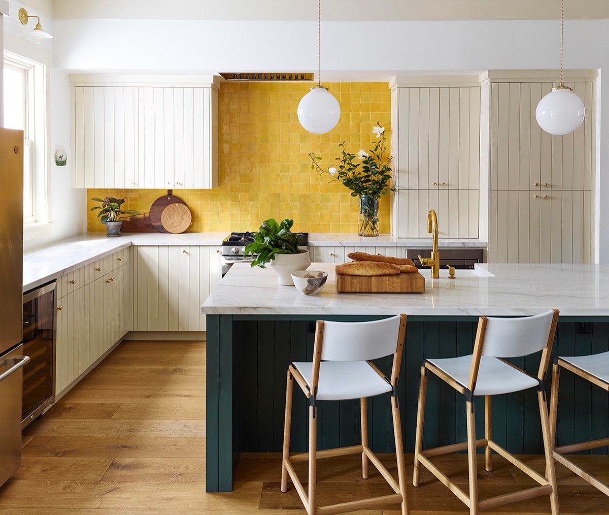 Vẻ đẹp sang trọng của gian bếp đến từ bàn đảo màu xanh lá đậm và mảng tường ốp gạch màu vàng chanh kết hợp sắc trắng chủ đạo. 