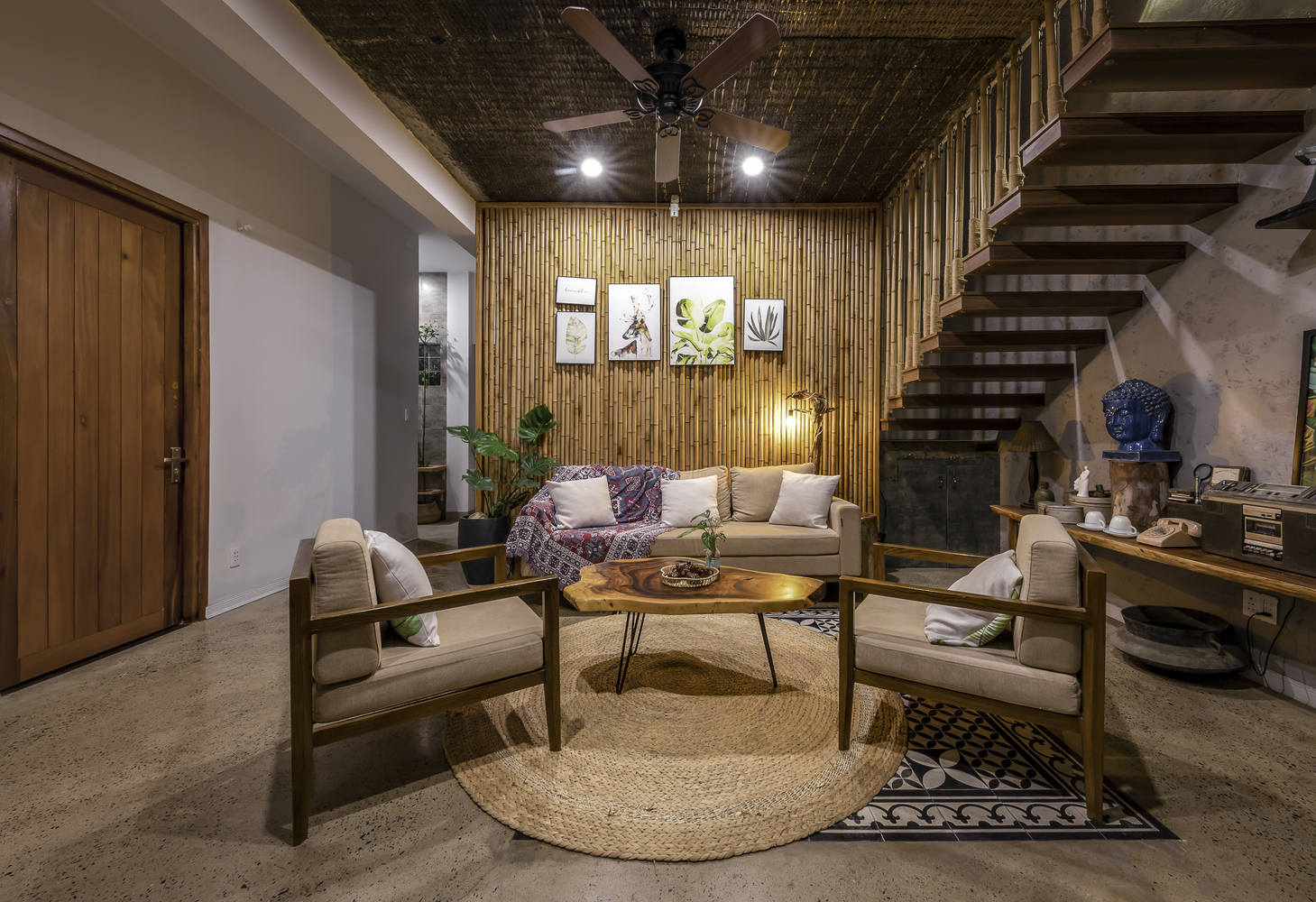 Không gian phòng khách khá rộng rãi, sử dụng nội thất làm bằng chất liệu tự nhiên như bàn ghế gỗ, thảm cói, tre ốp tường.