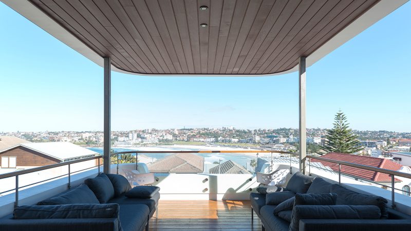 phòng khách ngoài trời với ghế sofa màu xanh dương, hướng nhìn ra bãi biển Bondi