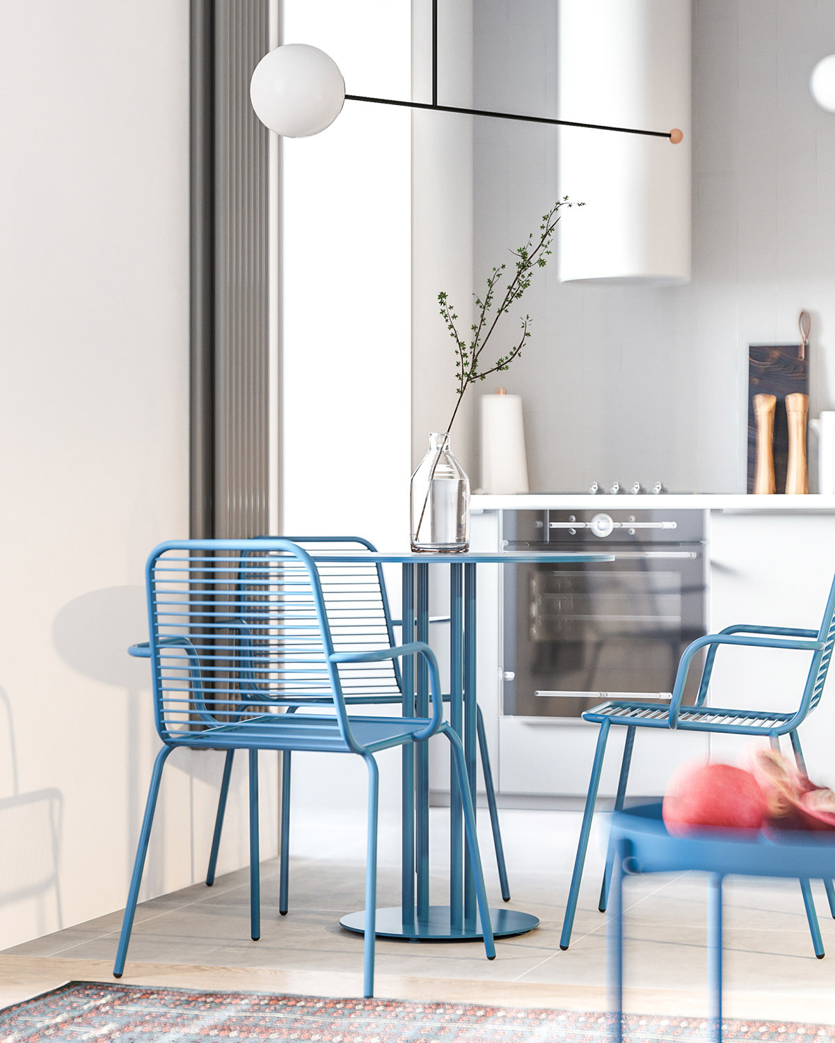 Những chiếc ghế màu xanh và bàn ăn tròn phù hợp với nền tủ bếp trắng và bức tường xám phía đối diện.