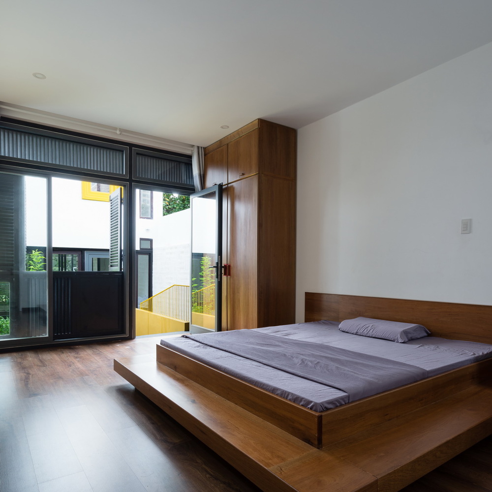 phòng ngủ rộng thoáng với giường gỗ thấp sàn, ga gối màu tím nhạt