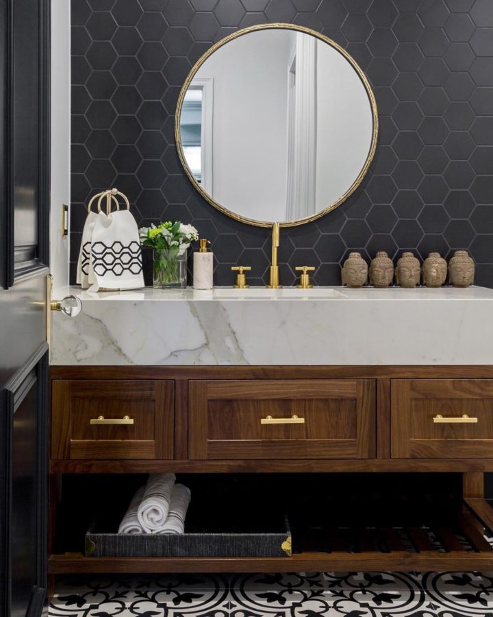 góc phòng tắm với gạch lát bóng mờ màu xám đen, gương tròn khung gỗ ấn tượng