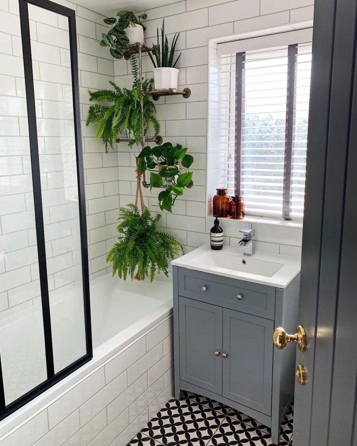 phòng tắm tối giản với gạch ốp tường màu trắng, gạch lát nền màu đen, cây xanh trên giá kệ