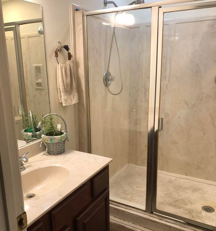 góc phòng tắm với bồn rửa sứ, cửa kính trong suốt, gương gán tường, vòng treo khăn tắm, cặp tóc