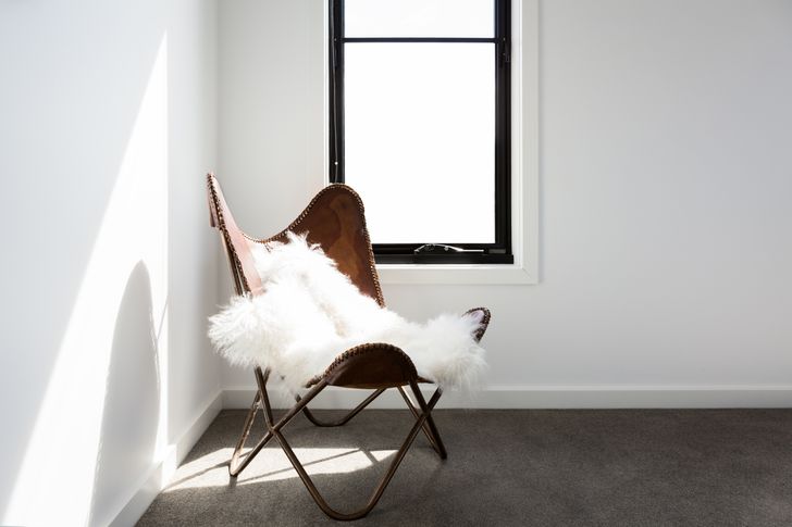 hình ảnh góc phòng với ghế tựa da nâu, thảm lông màu trắng, được bài trí cạnh khung cửa sổ kính ngập tràn ánh sáng