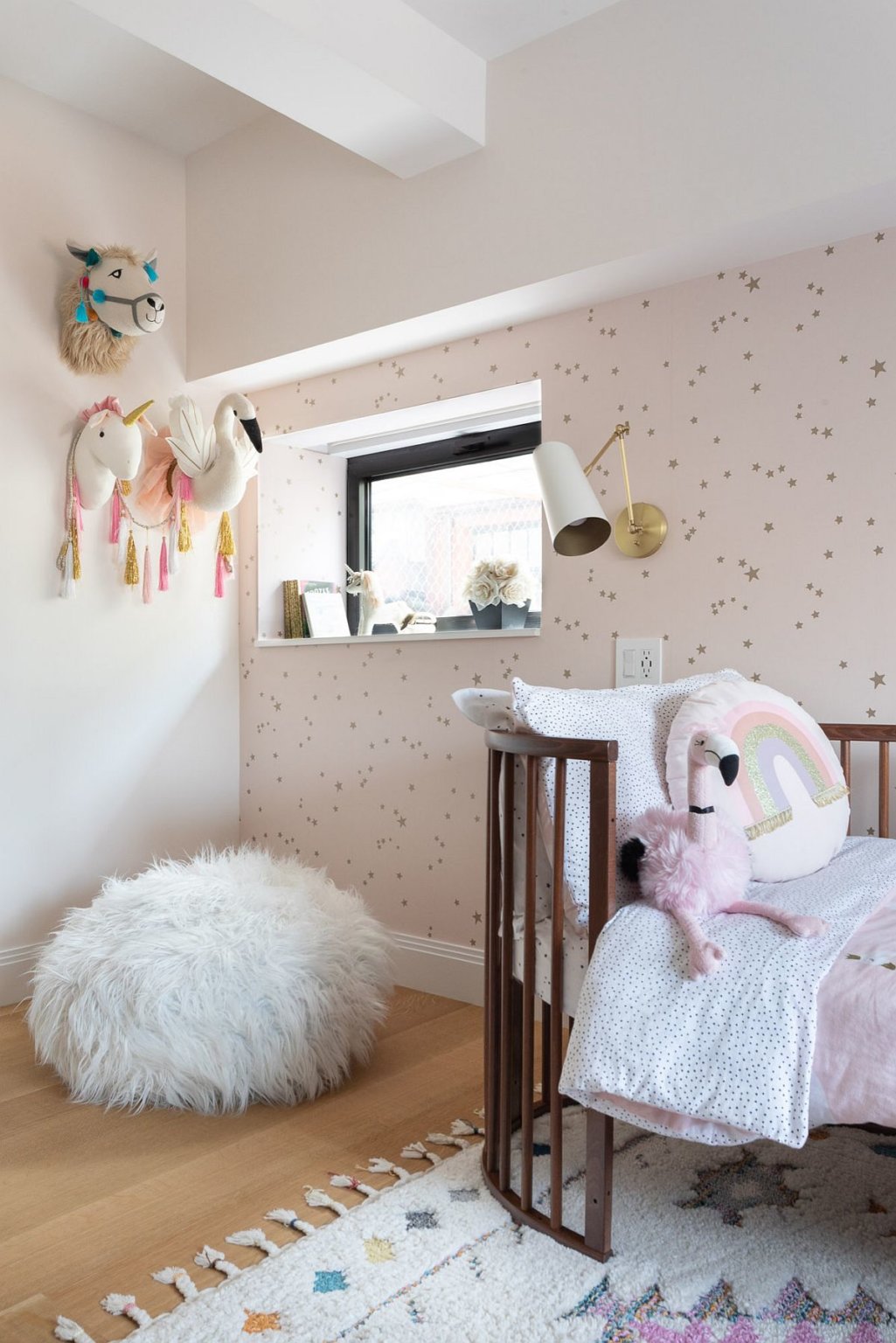 phòng ngủ trẻ em nổi bật với giấy dán tường màu hồng pastel, họa tiết ngôi sao, giường sơ sinh