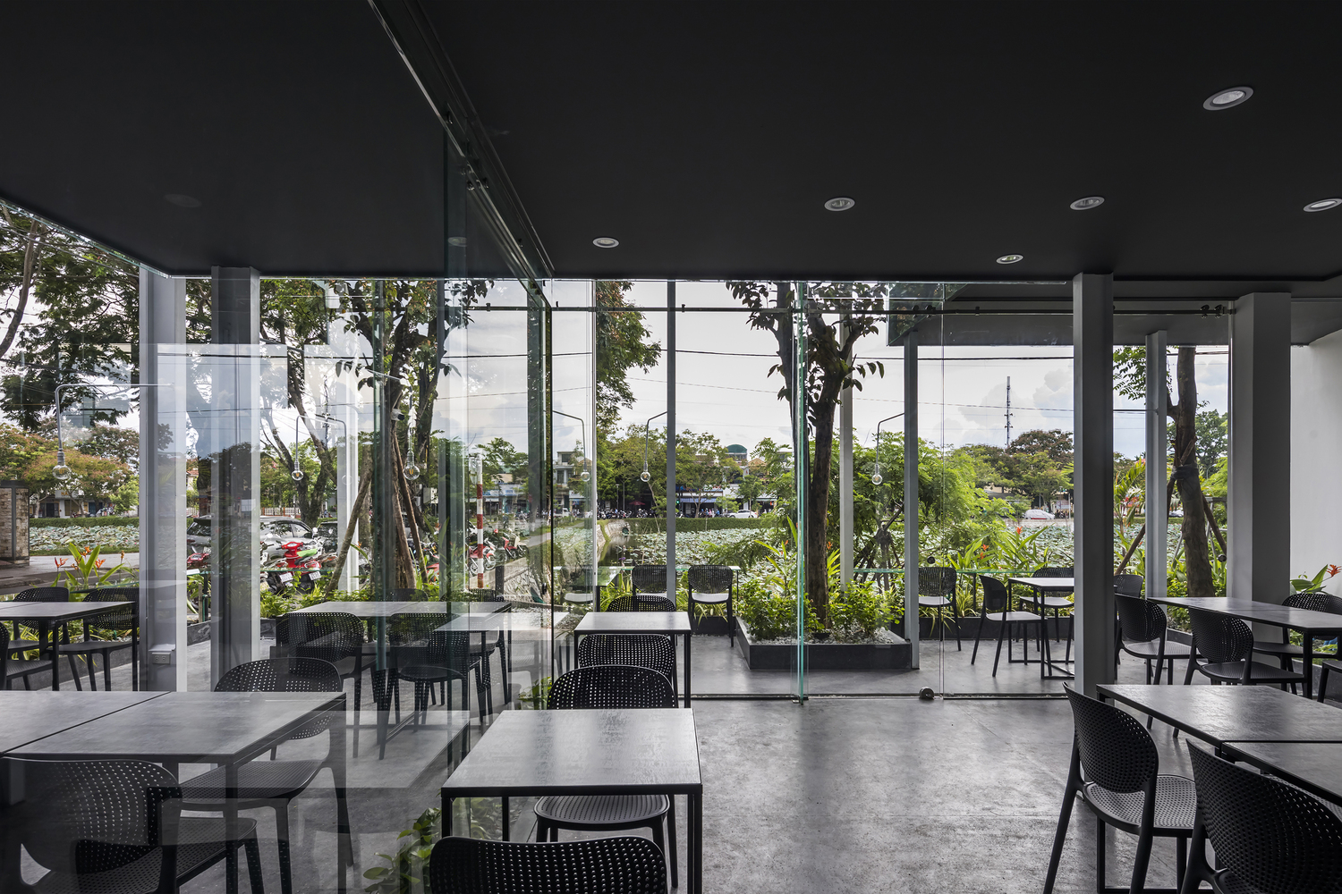 không gian bên trong quán cà phê độc đáo với tường kính trong suốt hướng nhìn ra cây xanh bên ngoài