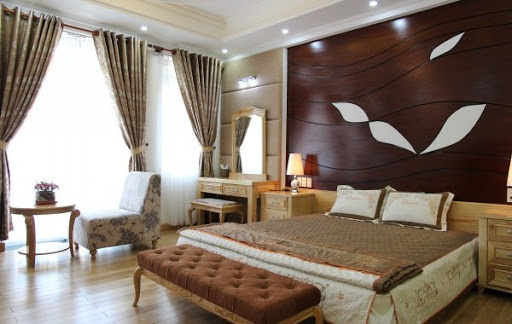 Mẫu phòng ngủ master mang hơi hướng phong cách truyền thống với tường đầu giường ốp gỗ sẫm màu, hệ rèm cửa dày dặn điều tiết ánh sáng tự nhiên vào phòng.