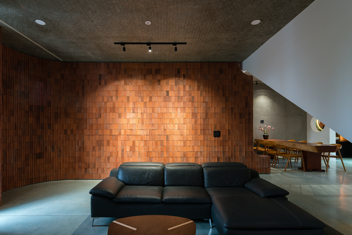 hình ảnh phòng khách với sofa da màu đen, tường ốp gạch màu nâu đất