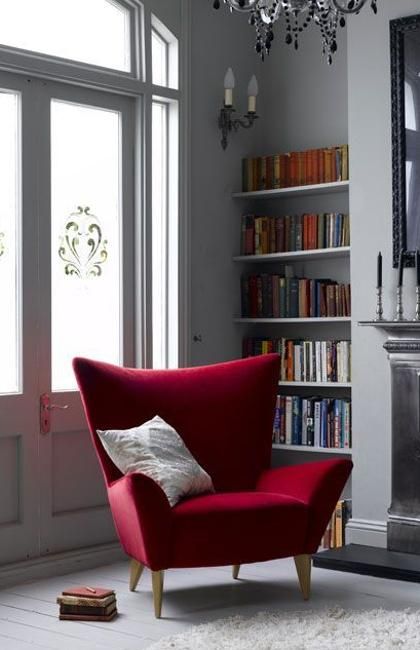 hình ảnh cận cảnh ghế ngồi thư giãn có tựa lưng màu đỏ, cạnh đó là giá sách, cửa sổ kính