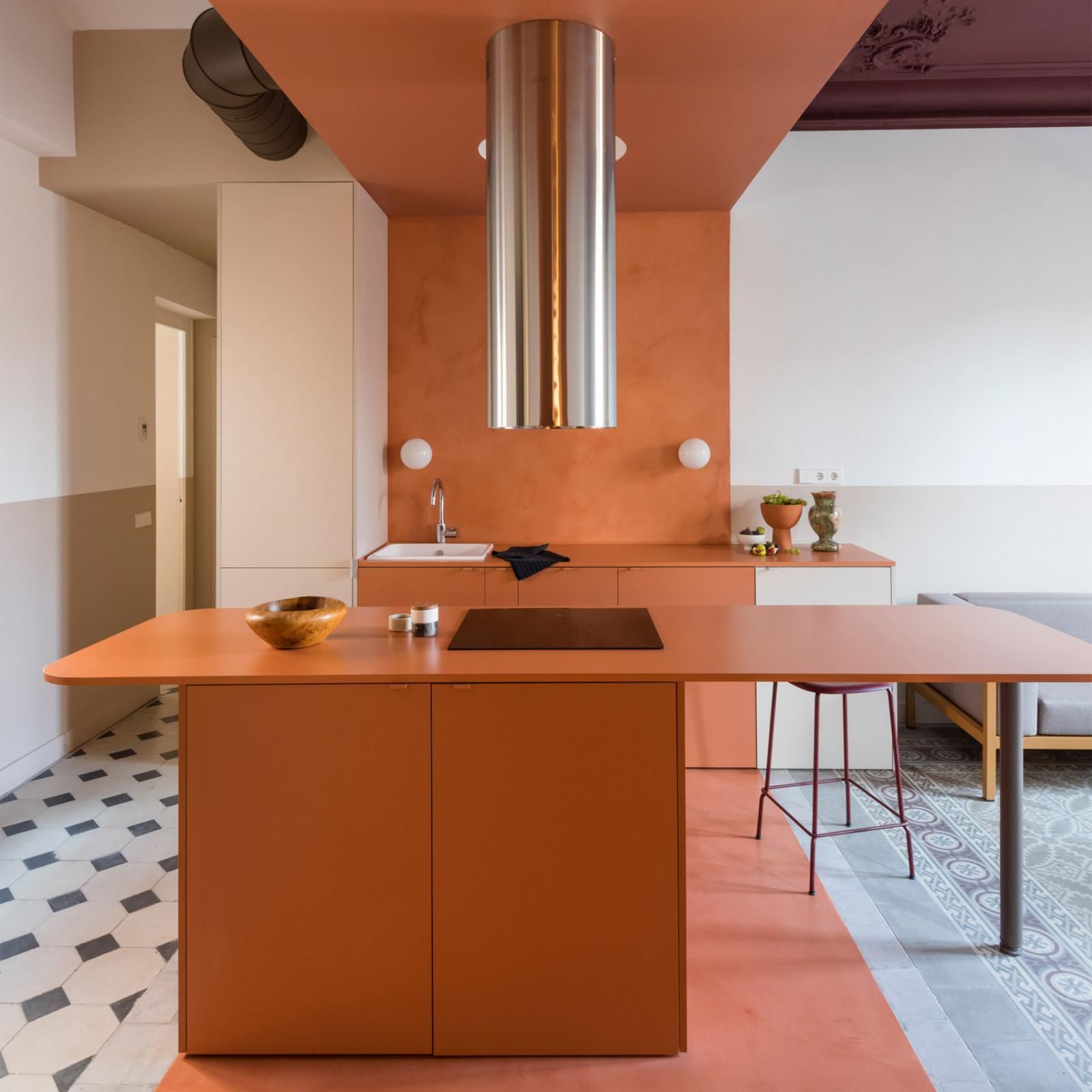 Phòng bếp trong căn hộ nghỉ dưỡng ở Tây Ban Nha với xi măng màu đất nung lót trần, tường và sàn nhà. Những bề mặt ấm áp này được bổ sung bởi tủ bếp dưới, quầy bar ăn sáng trung tâm tương phản với gạch lát sàn hoa văn.