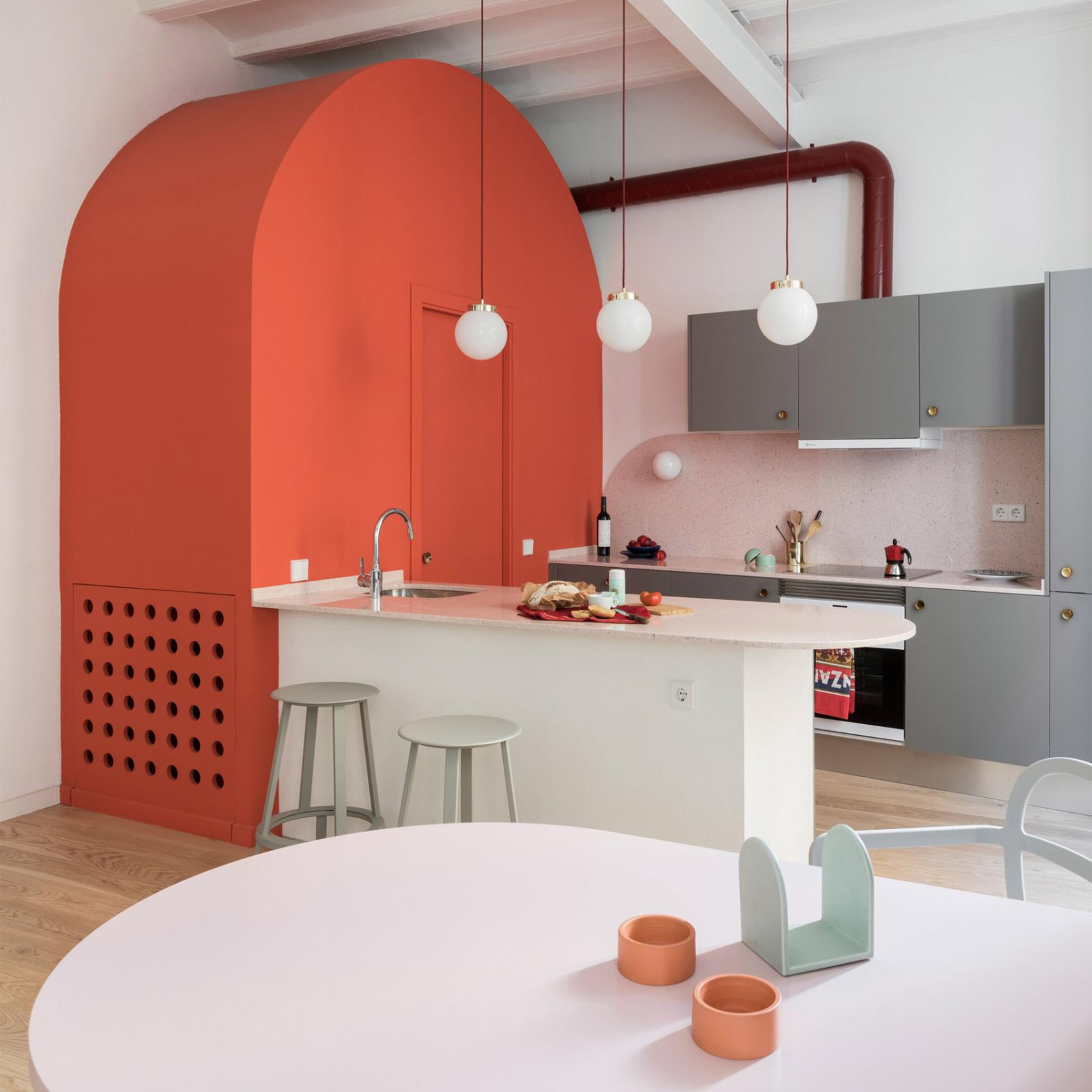 Phòng bếp trong căn hộ phong cách thế kỷ XIII ở Tây Ban Nha gây ấn tượng với thạch anh màu đỏ dùng để chế tác bàn ăn, được cân bằng bởi dụng cụ nhà bếp màu xám, tay cầm bằng đồng, khối vòm màu san hô giấu nhẹm nhà vệ sinh nhỏ.