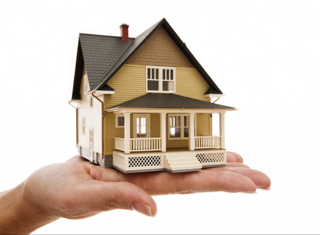 hình ảnh cận cảnh bàn tay đang nâng đỡ mô hình ngôi nhà, minh họa cho giao dịch mua bán nhà đất
