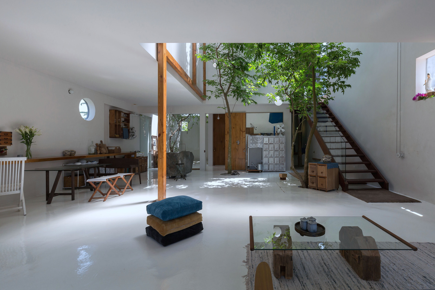 hình ảnh toàn cảnh không gian sinh hoạt chung ở tầng trệt ngôi nhà với cây xanh lớn trồng ở khoảng trống thông tầng