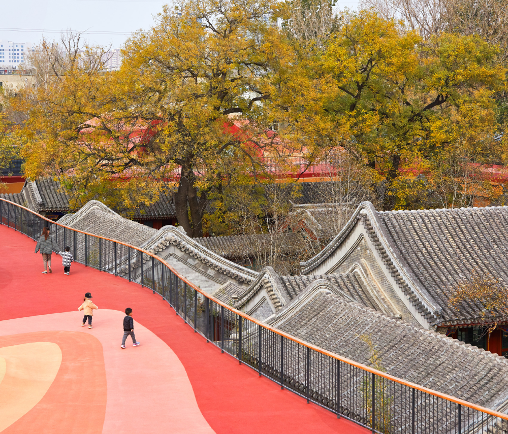 hình ảnh phần mái làm sân chơi cho trẻ sơn màu đỏ, cam, cạnh đó là cây cổ thủ lá vàng ươm