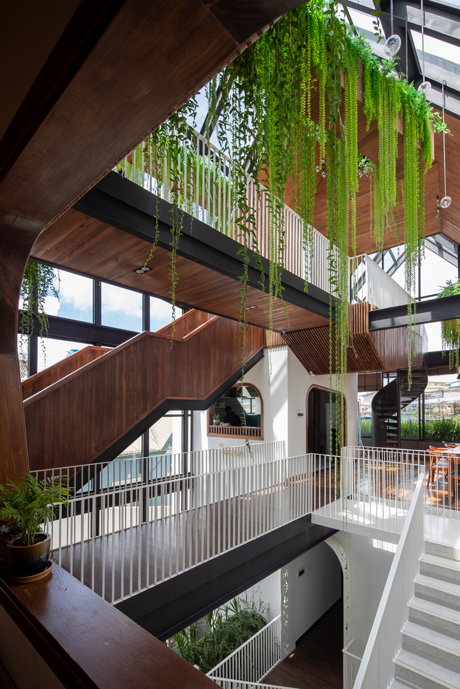 cận cảnh khu vực cầu thang trong homestay với cấu trúc gỗ kết hợp kim loại, cây xanh tạo điểm nhấn