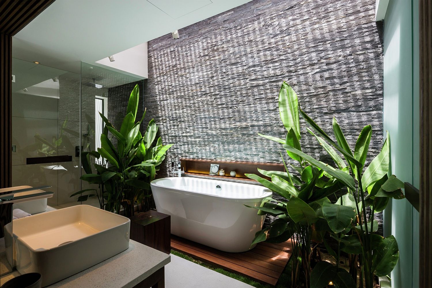 phòng tắm với bồn tắm sứ màu trắng, xung quanh là các loại cây cảnh nhiệt đới xanh tốt