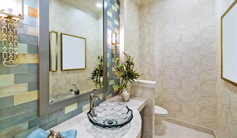 hình ảnh một góc phòng tắm với gương hình chữ nhật gắn tường, khung gương mạ vàng, tường ốp gạch vân đá cẩm thạch