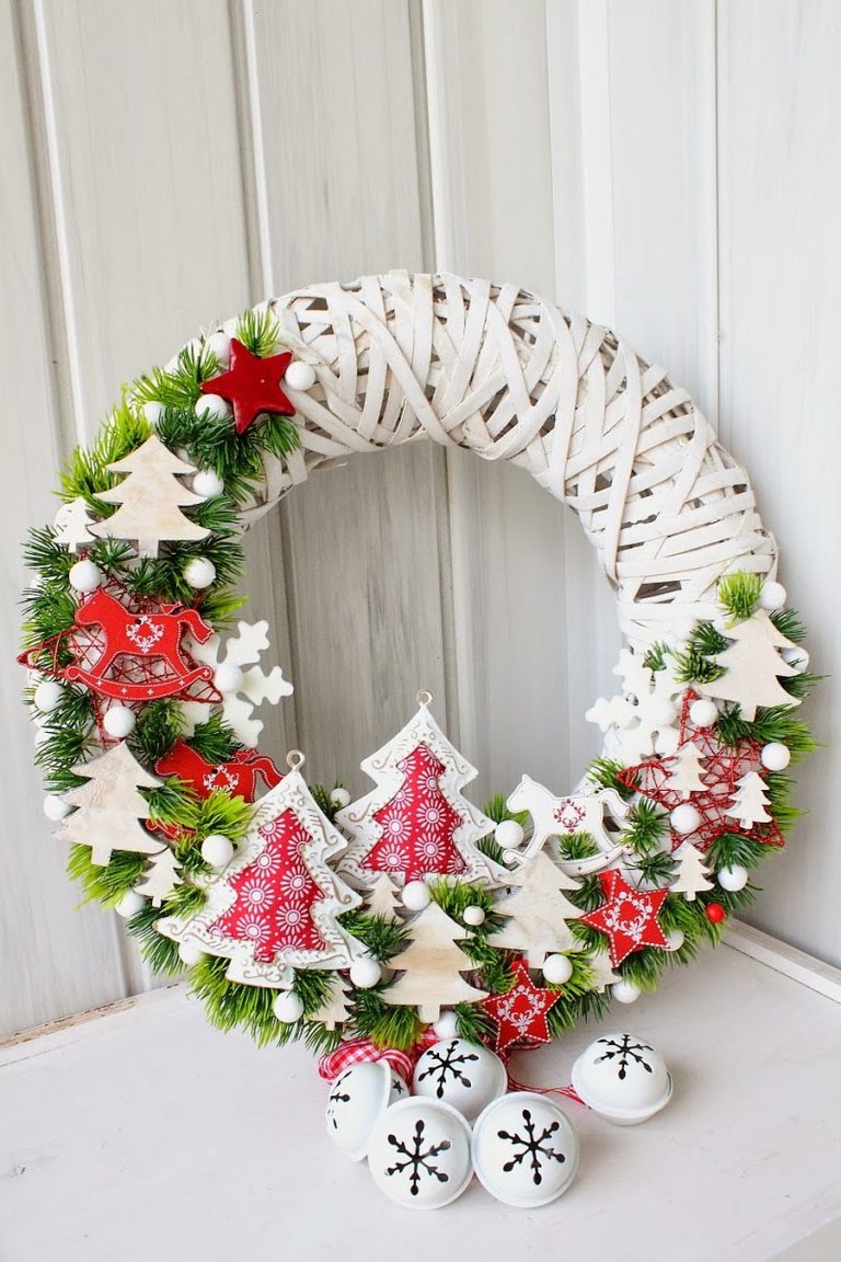 Hình ảnh cận cảnh vòng hoa Noel treo trên cánh cửa màu trắng xám