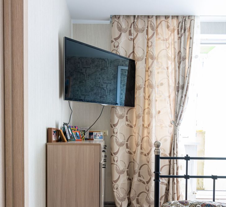 hình ảnh góc phòng ngủ với tivi gắn tường, rèm cửa