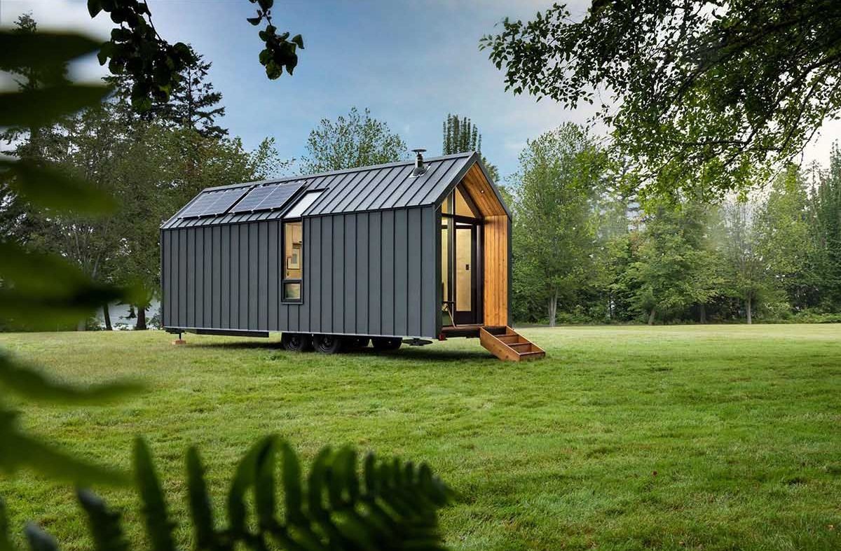 hình ảnh toàn cảnh ngôi nhà cabin với lớp vỏ kim loại màu xám đen đặt trên thảm cỏ xanh mướt