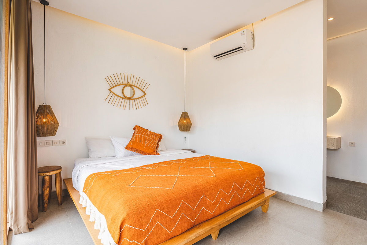 Phòng ngủ trong biệt thự 2 tầng được thiết kế với tông màu cam nhấn nhá. Đèn mặt dây chuyền đan móc mộc mạc đối xứng hai bên đầu giường cung cấp ánh sáng đọc sách.