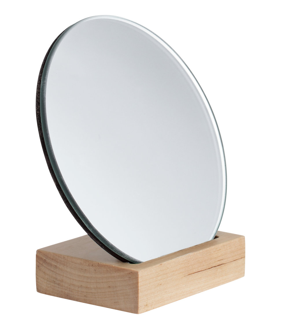 hình ảnh cận cảnh gương tròn đặt trên đế gỗ màu sáng
