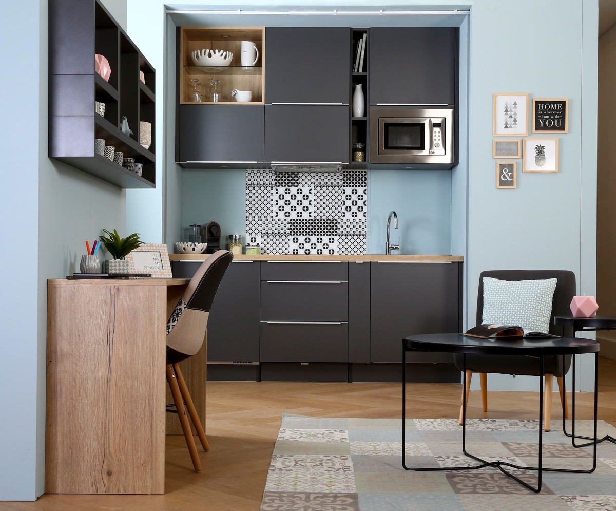 hình ảnh phòng bếp với hệ tủ màu đen xám, tích hợp ngăn để lò vi sóng, cạnh đó là bàn ăn, bàn làm việc