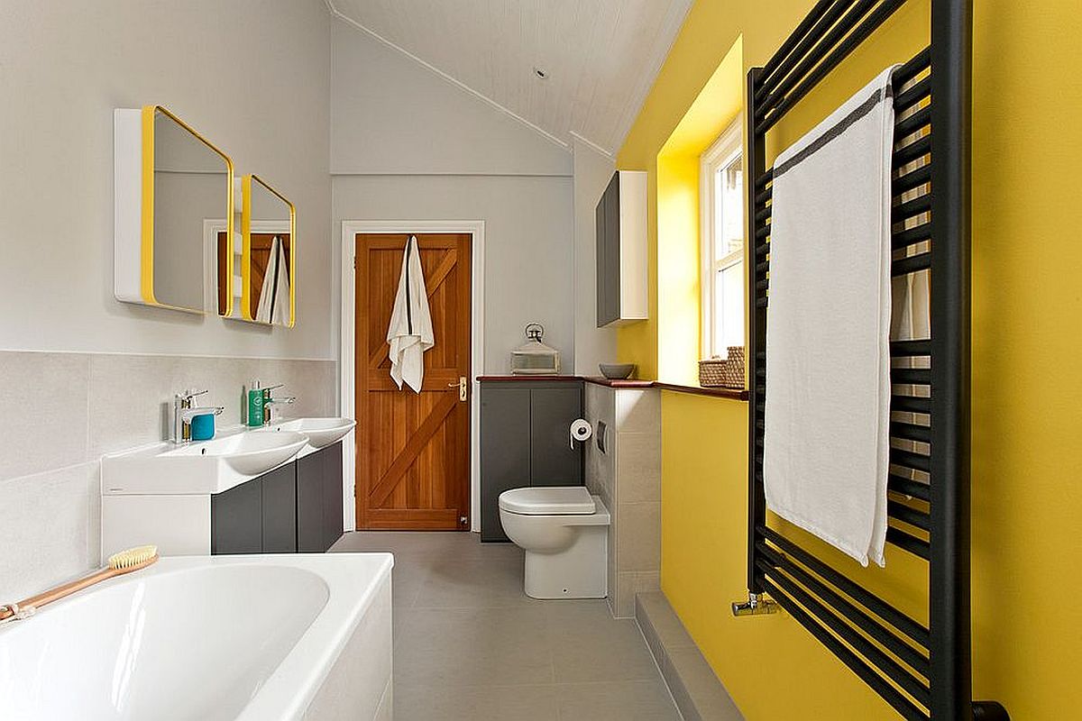 Bức tường màu vàng nổi bật tạo điểm nhấn cho phòng tắm hiện đại màu xám, trắng.