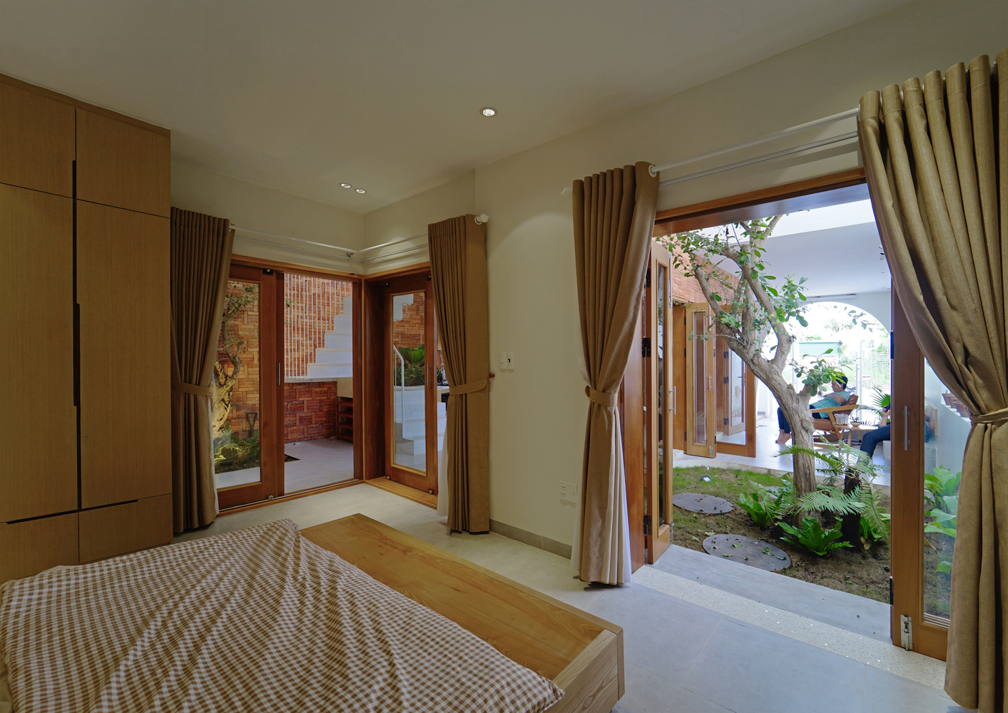 Phòng ngủ có thiết kế đơn giản, thoáng mở với hệ cửa lớn nhìn ra sân vườn.