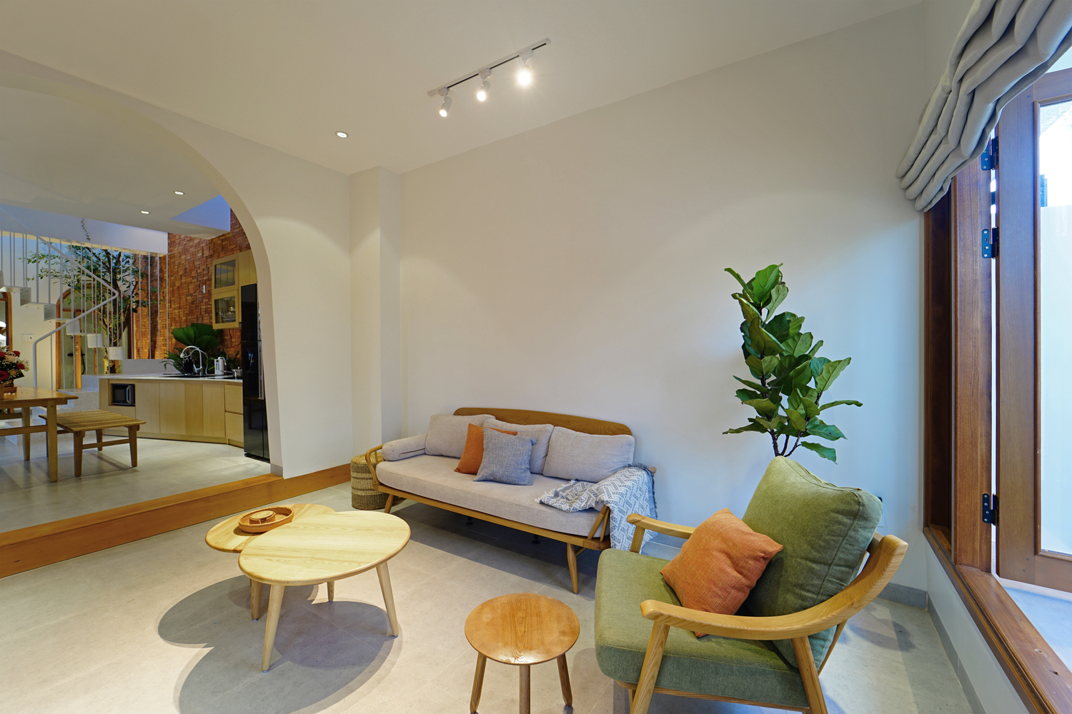 hình ảnh phòng khách nhà phố với tường sơn trắng, bàn trà gỗ đôi hình tròn, sofa gỗ lót đệm màu xám và xanh nõn chuối