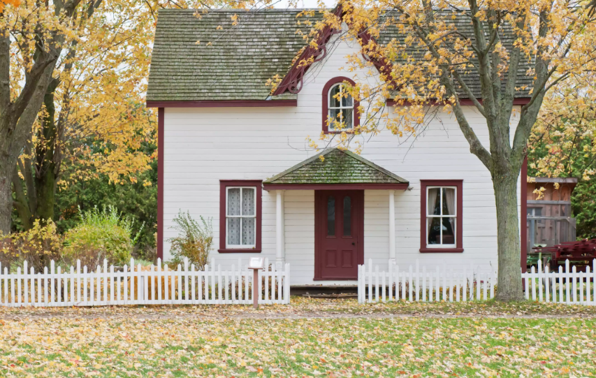 hình ảnh minh họa cho ngôi nhà có phong thủy tốt với mái ngói xám, sơn tường trắng nhấn nhá đỏ đun, nằm dưới tán những cây lớn lá vàng