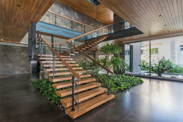 Cầu thang hiện đại với cây xanh bên dưới tạo thêm sự tươi mới cho không gian bên trong.