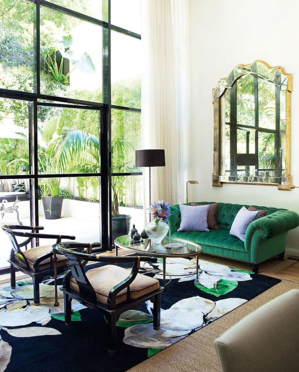 Ghế đi văng màu xanh lá cây đậm và sang trọng tạo điểm nhấn tinh tế cho phòng khách tràn ngập ánh sáng này.