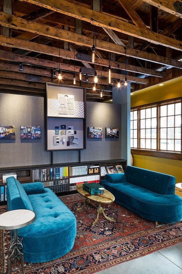 hình ảnh phòng khách với dầm gỗ lộ thiên, ghế sofa màu xanh ngọc, thảm trải thổ cẩm