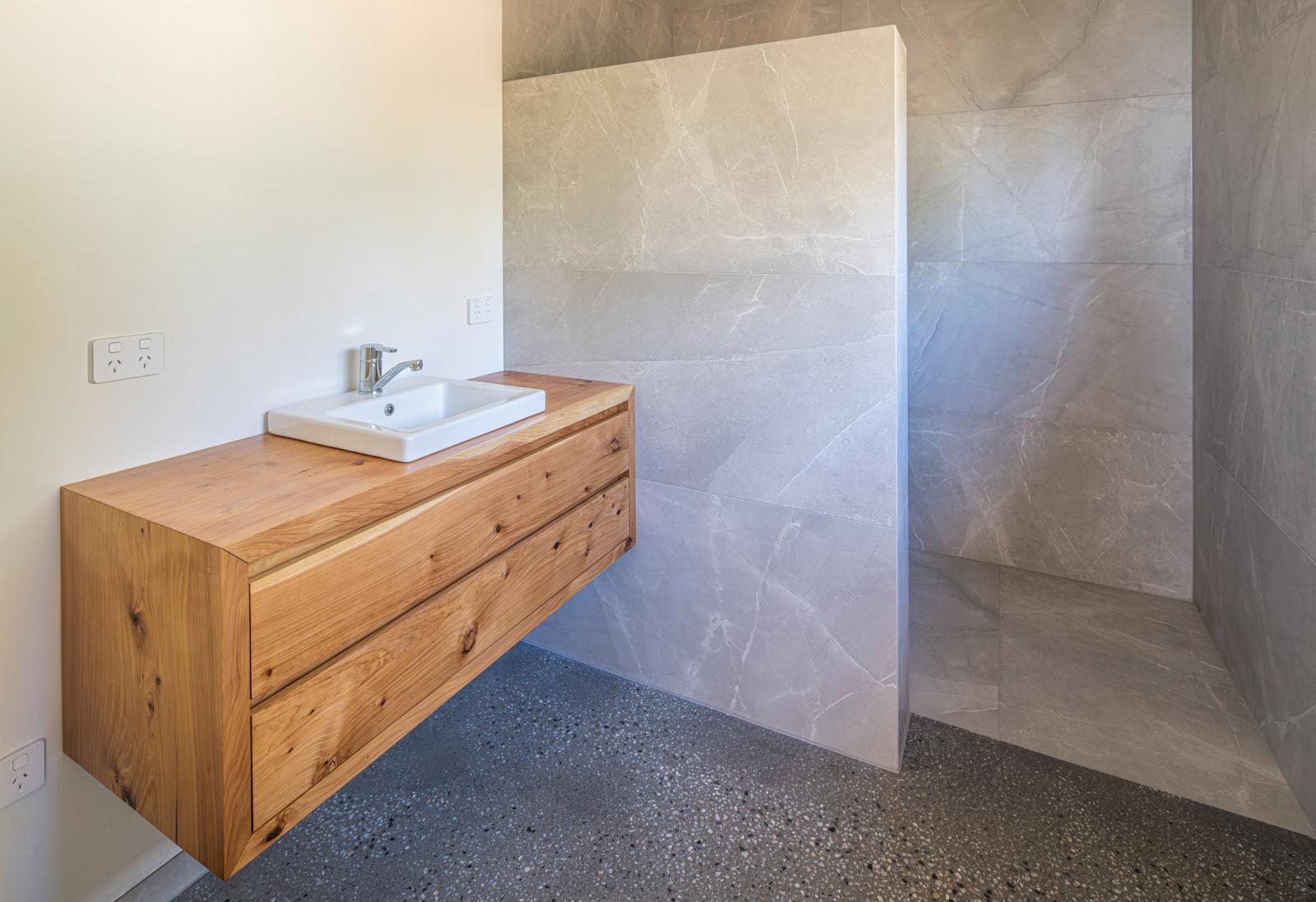 Phòng tắm phong cách tối giản với bệ gỗ mộc tạo điểm nhấn ấm áp.