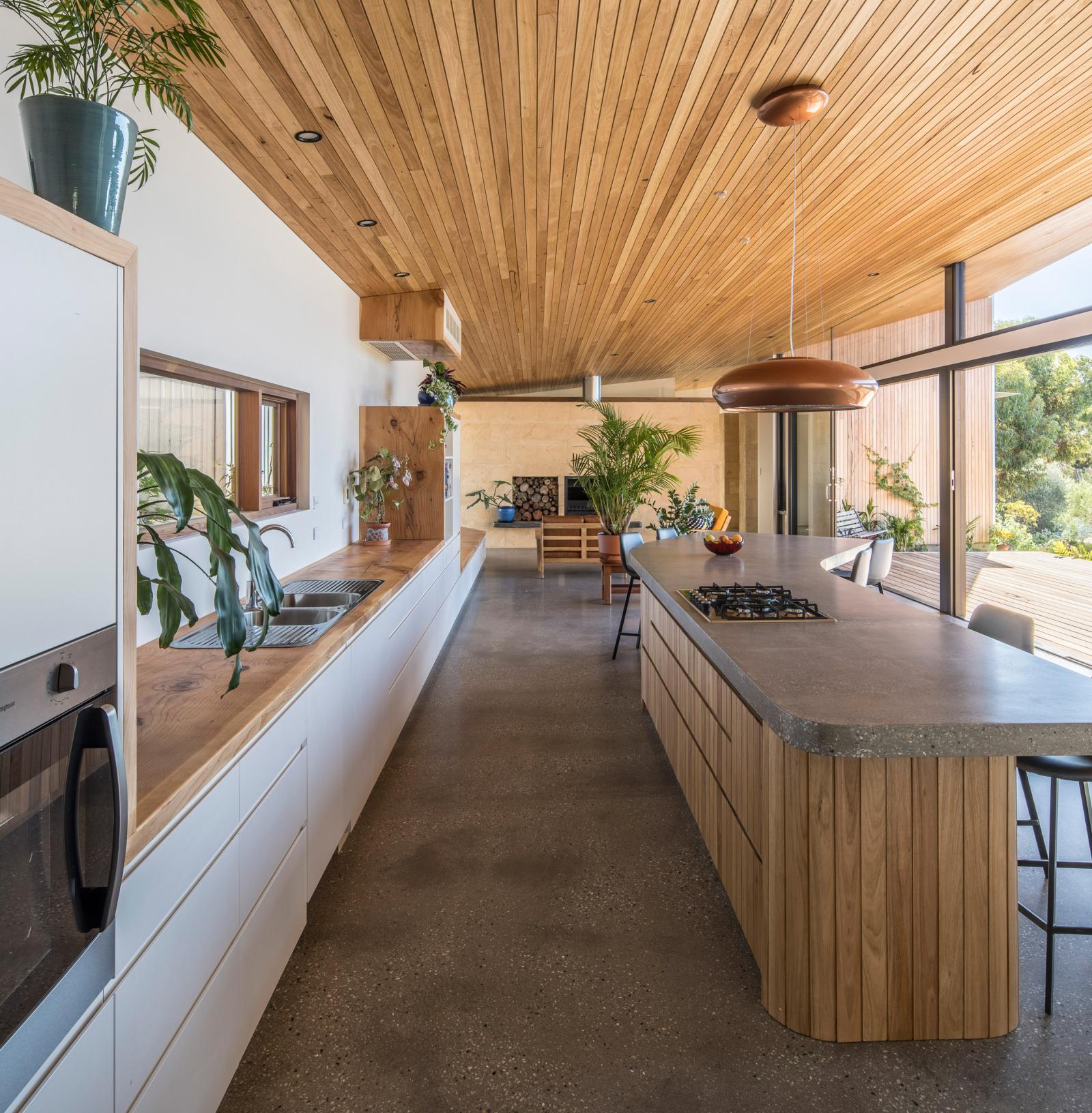 hình ảnh toàn cảnh phòng bếp ăn trong nhà vườn với sàn bê tông mài, trần hiên ốp gỗ sáng màu