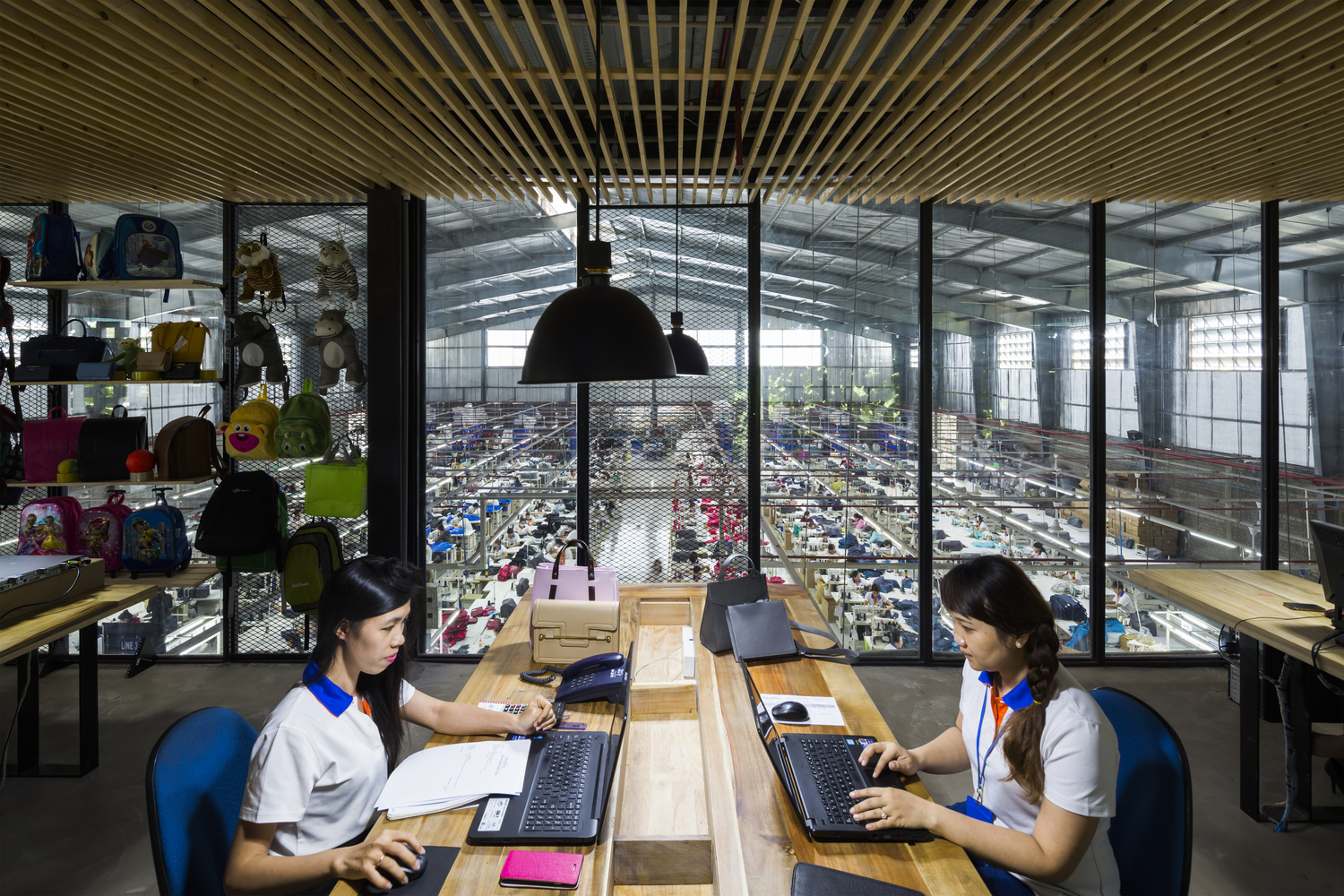 hình ảnh cận cảnh văn phòng làm việc với hai nữ nhân viên ngồi máy tính, xung quanh là giá kệ trưng bày sản phẩm