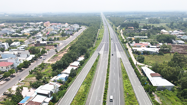 hình ảnh một tuyến cao tốc nhìn từ trên cao với nhiều làn đường, ô tô qua lại, hai bên là khu dân cư, cây xanh