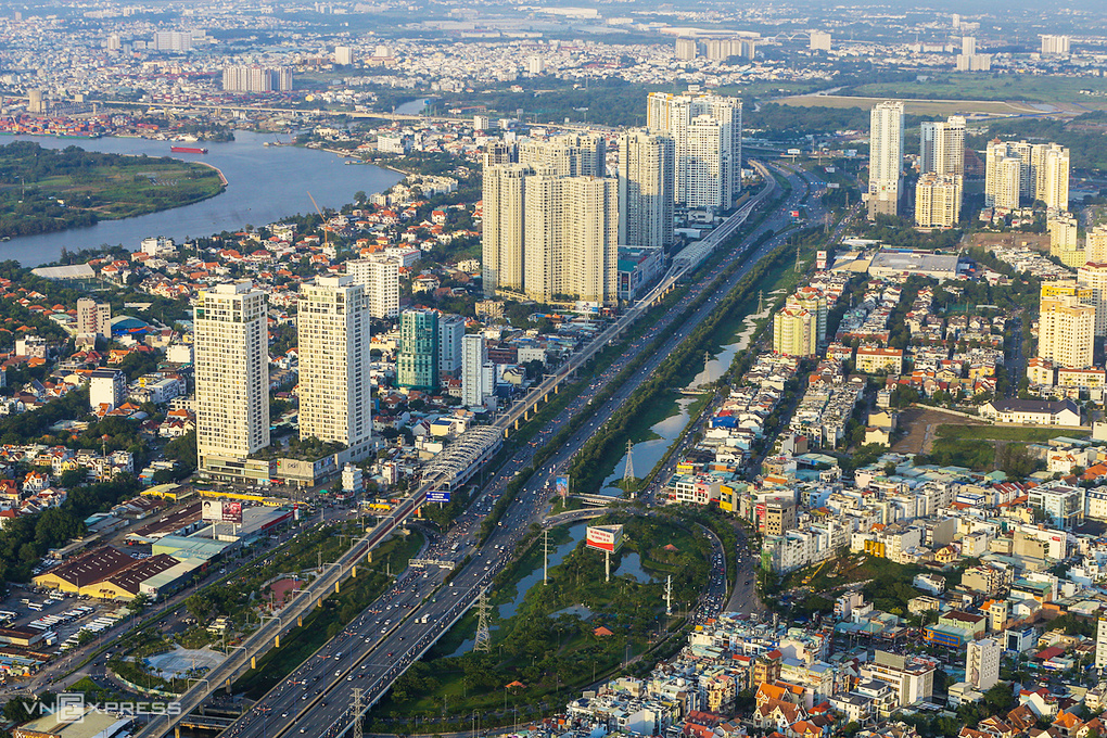 hình ảnh một góc thành phố nhìn từ trên cao với nhiều tòa nhà cao tầng xen kẽ khu dân cư thấp tầng, cây xanh, sông nước