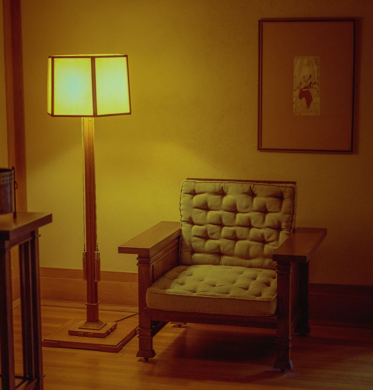 hình ảnh cận cảnh đèn sàn với ánh sáng vàng đặt cạnh ghế tựa 