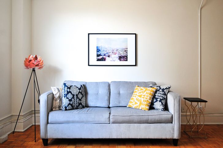 hình ảnh phòng khách với sofa màu xanh sáng, tranh treo tường, đèn sàn độc đáo