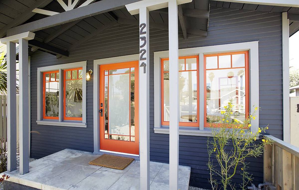 Khung cửa và cửa sổ màu cam mang lại độ sáng cho ngoại thất ngôi nhà màu xám đậm.